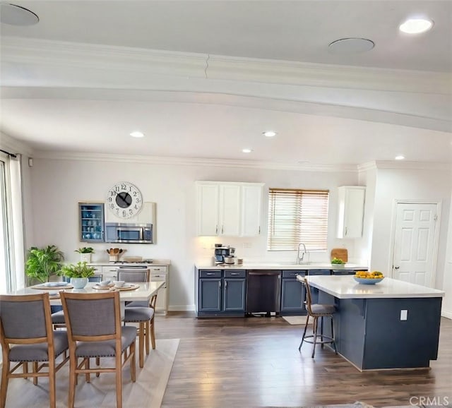 kitchen featuring black dishwasher, dark wood-style floors, stainless steel microwave, light countertops, and white cabinetry