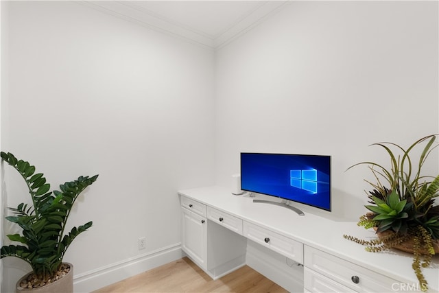 office with light hardwood / wood-style floors, built in desk, and ornamental molding