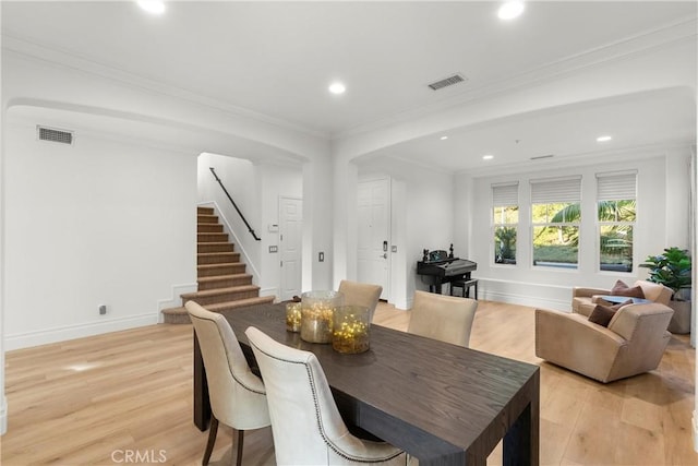 dining space with ornamental molding and light hardwood / wood-style flooring