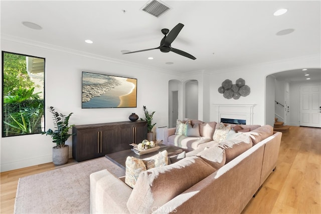 living room with ceiling fan, ornamental molding, and light hardwood / wood-style floors