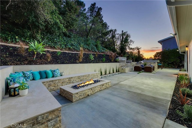 patio terrace at dusk with an outdoor living space with a fire pit