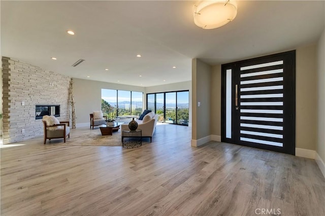 foyer entrance featuring a stone fireplace and light hardwood / wood-style floors