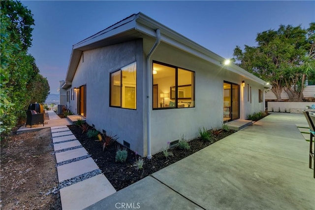 property exterior at dusk featuring a patio