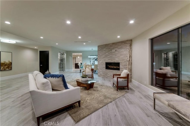 living room featuring a stone fireplace and light wood-type flooring