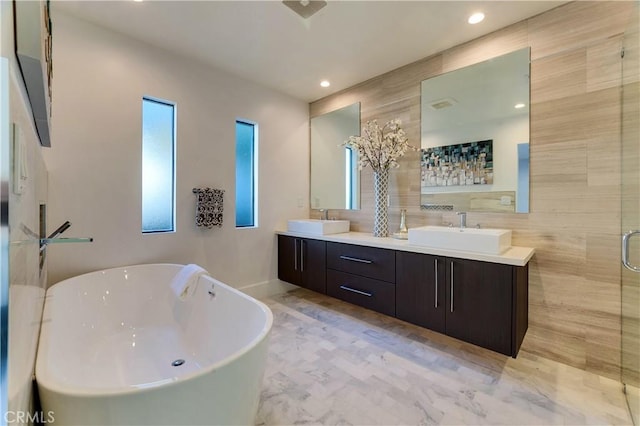 bathroom featuring shower with separate bathtub, tile walls, and vanity