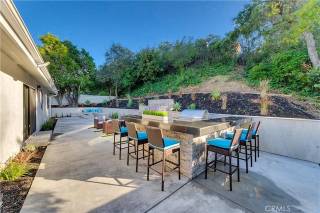 view of patio / terrace featuring an outdoor kitchen, grilling area, and an outdoor bar