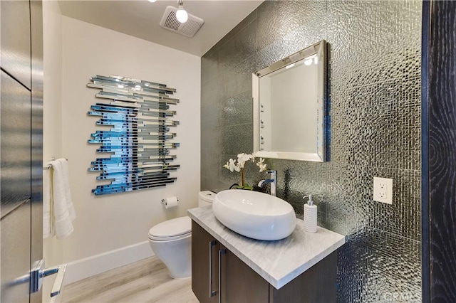 bathroom featuring vanity, backsplash, wood-type flooring, and toilet