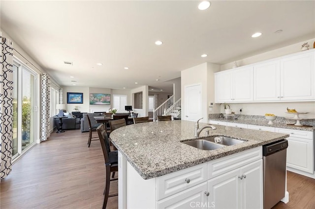 kitchen featuring white cabinetry, dishwasher, wood-type flooring, sink, and a center island with sink