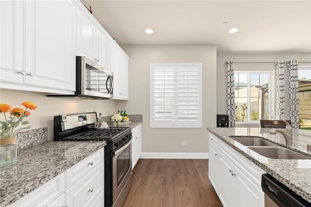 kitchen featuring white cabinetry, stainless steel appliances, and light stone counters