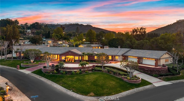 view of front of property with a garage, a mountain view, and a lawn