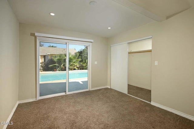 unfurnished bedroom featuring access to exterior, a closet, and dark colored carpet