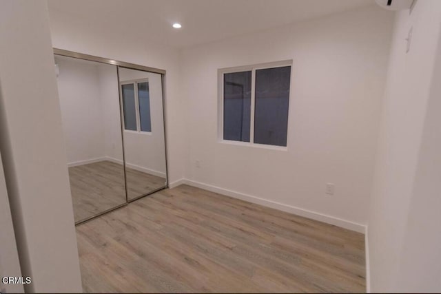 unfurnished bedroom with light hardwood / wood-style flooring and a closet