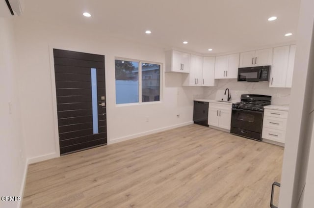 kitchen featuring white cabinetry, sink, a wall unit AC, and black appliances