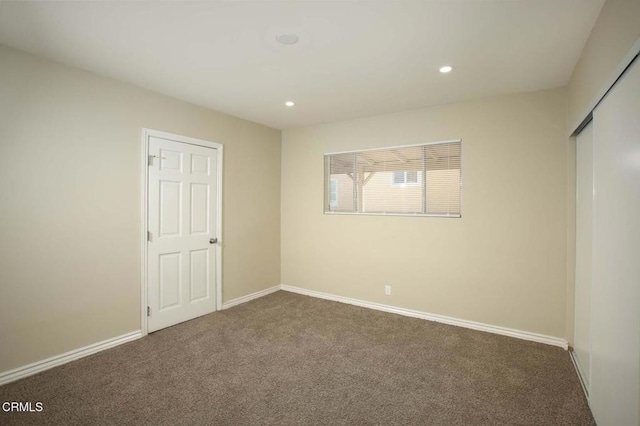 unfurnished bedroom featuring a closet and dark colored carpet