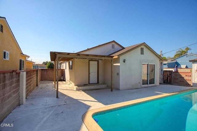 back of property with a fenced in pool and a patio area