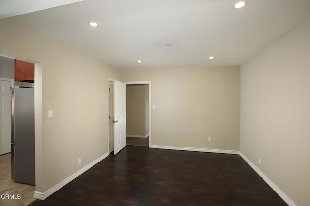 unfurnished bedroom featuring stainless steel built in fridge and dark wood-type flooring