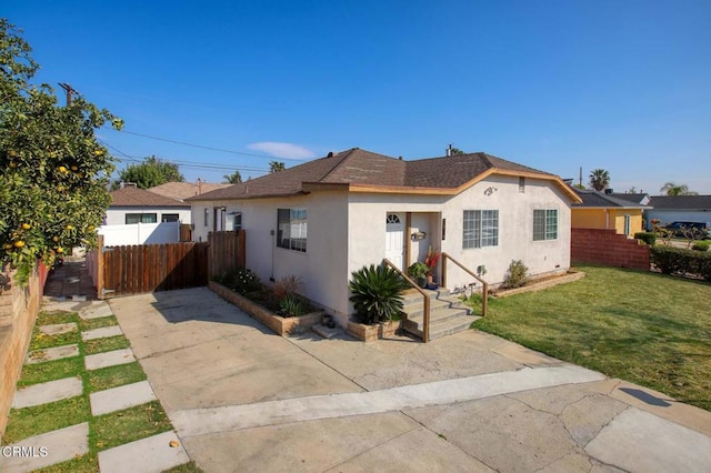 bungalow with a front lawn, roof with shingles, fence, and stucco siding