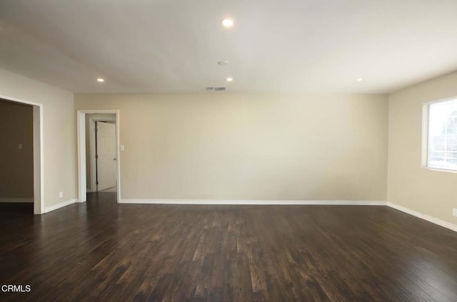 unfurnished room featuring dark wood-style floors, visible vents, baseboards, and recessed lighting