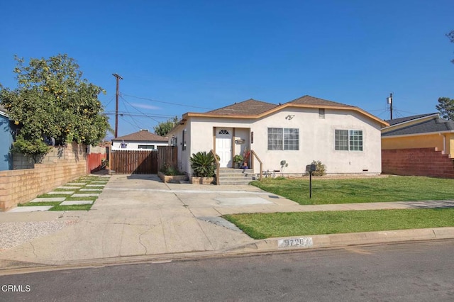 view of front of home with a front yard, fence, and stucco siding