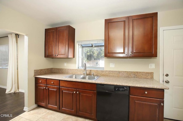 kitchen with light tile patterned floors, black dishwasher, baseboards, light countertops, and a sink