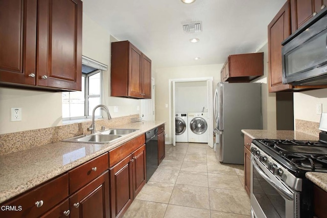 kitchen featuring light tile patterned flooring, stainless steel appliances, separate washer and dryer, a sink, and visible vents