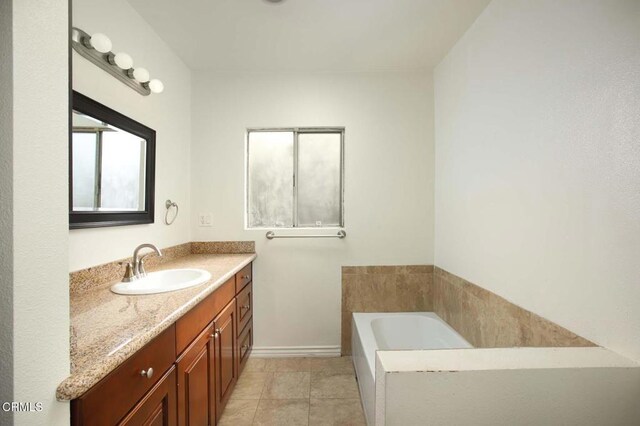 bathroom with tile patterned flooring, vanity, baseboards, and a bath