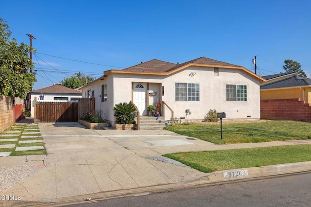 view of front of property featuring a front lawn, fence, and stucco siding