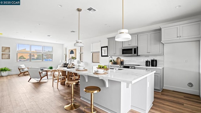 kitchen with gray cabinets, pendant lighting, sink, a kitchen island with sink, and stainless steel appliances