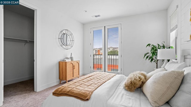 carpeted bedroom with a spacious closet, access to outside, and a closet