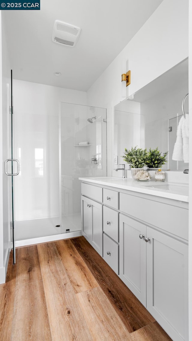 bathroom featuring vanity, hardwood / wood-style floors, and a shower with shower door