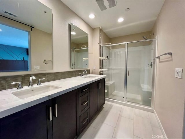 bathroom featuring vanity, backsplash, and a shower with shower door