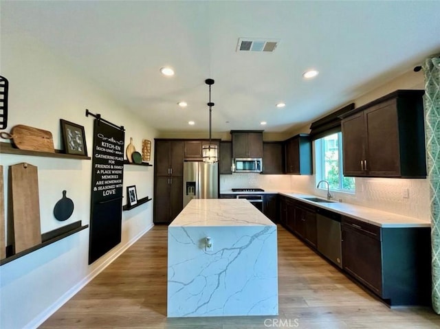 kitchen with sink, tasteful backsplash, decorative light fixtures, a center island, and stainless steel appliances