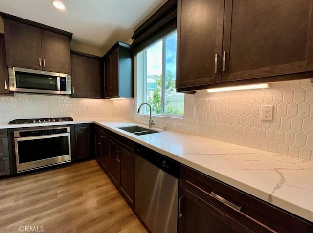 kitchen with sink, light hardwood / wood-style flooring, stainless steel appliances, dark brown cabinetry, and decorative backsplash