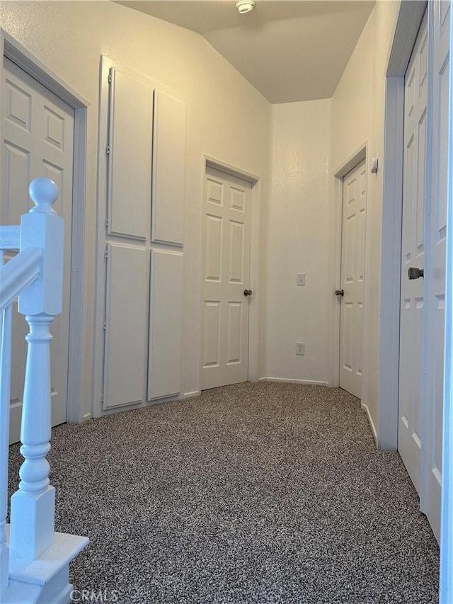 hall with carpet flooring and vaulted ceiling