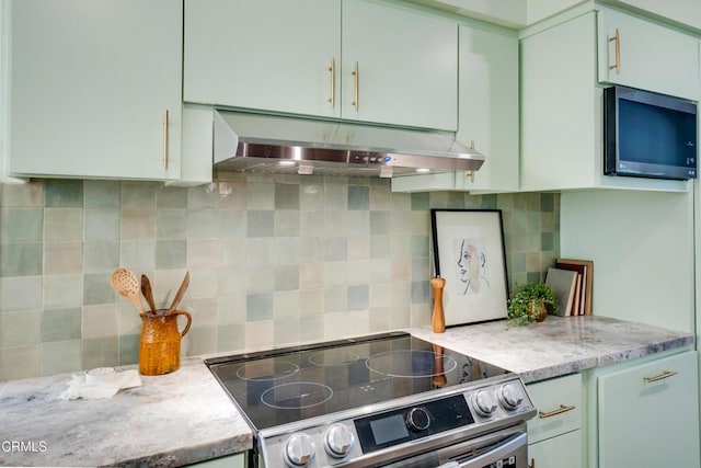 kitchen with stainless steel electric stove, green cabinets, backsplash, and light stone counters