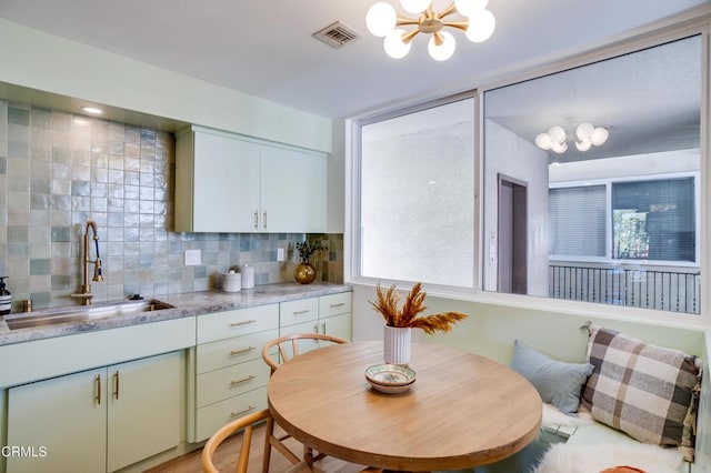 kitchen featuring a notable chandelier, plenty of natural light, sink, and backsplash