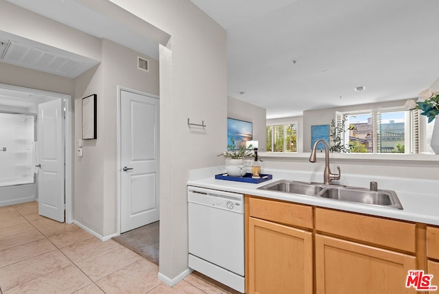 kitchen featuring white dishwasher, light brown cabinetry, sink, and light tile patterned floors