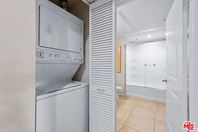 clothes washing area with light tile patterned flooring and stacked washer and dryer