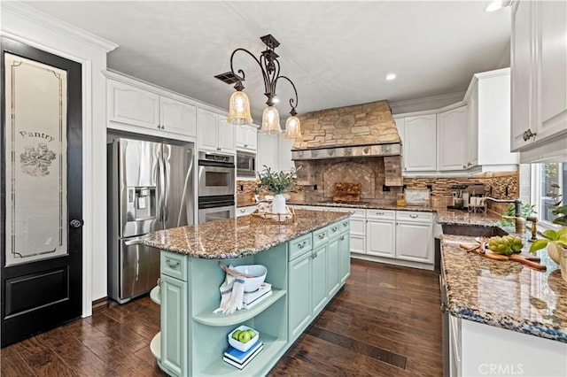 kitchen with a center island, appliances with stainless steel finishes, custom range hood, pendant lighting, and white cabinets