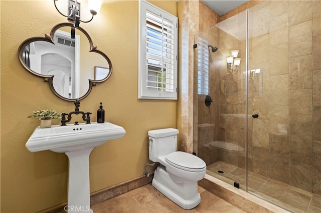 bathroom featuring a shower with door, tile patterned flooring, and toilet