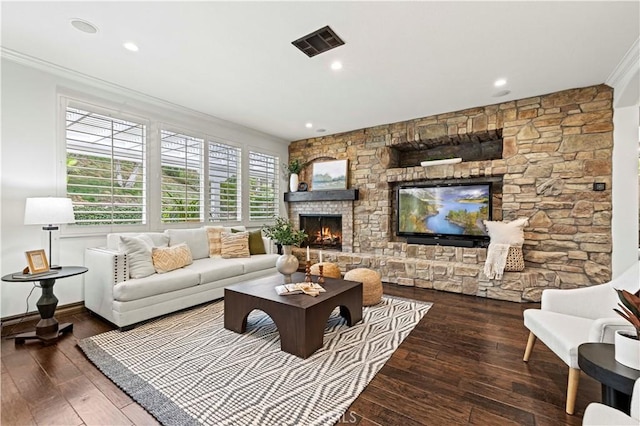 living room featuring crown molding, a stone fireplace, and dark wood-type flooring