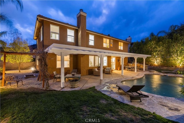 back house at dusk featuring a yard, a patio area, and an outdoor living space with a fire pit