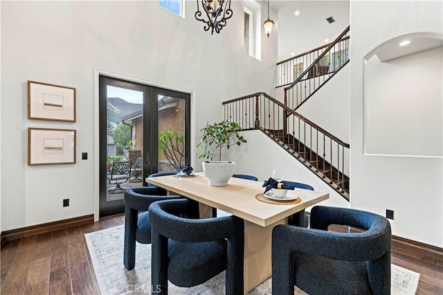 dining room featuring a high ceiling, dark wood-type flooring, a notable chandelier, and french doors