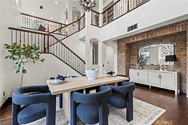 dining area with a towering ceiling and dark hardwood / wood-style floors