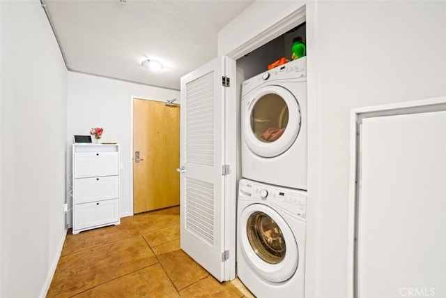 clothes washing area with stacked washing maching and dryer and light tile patterned floors