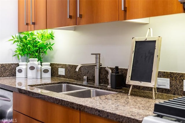 kitchen with sink, stainless steel dishwasher, and dark stone counters