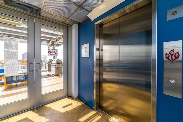 entryway with french doors, elevator, and concrete flooring