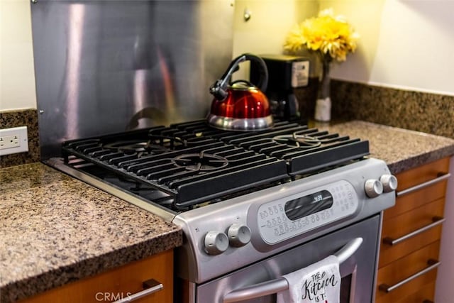 details featuring stainless steel range with gas stovetop and dark stone countertops