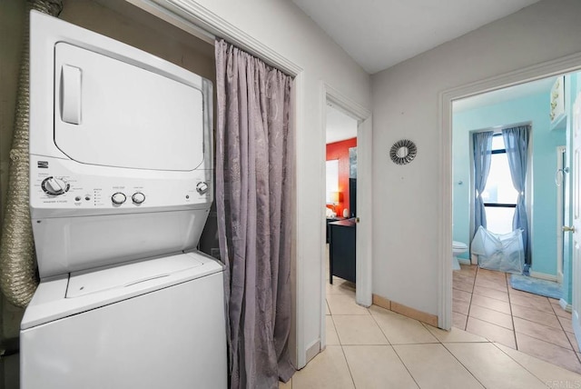 laundry area with stacked washer / dryer and light tile patterned floors