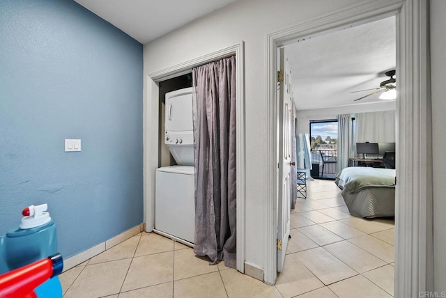 corridor with light tile patterned flooring and stacked washing maching and dryer